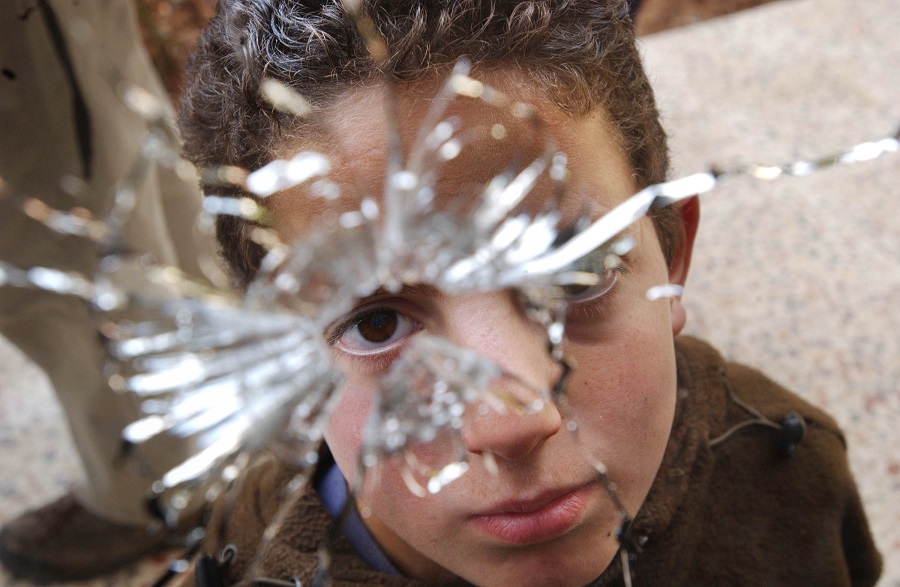 Eleven-year-old Abdallah looks through the hole left by the bullet that killed her mother Manal Sami Sufran in her home April 11, 2002 in the West Bank town of Ramallah. Sufran was killed April 10, 2002 when a bullet punched into her home and killed her as she sat with her children on a couch. (Photo by Chris Hondros/Getty Images)